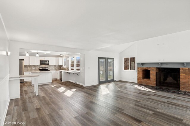 unfurnished living room featuring baseboards, lofted ceiling, wood finished floors, and a fireplace