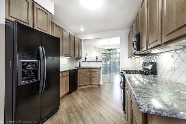 418 Bay Tree Cir, Vernon Hills, IL 60061 - kitchen with black appliances, light wood-style floors, a chandelier, decorative backsplash, and light stone counters