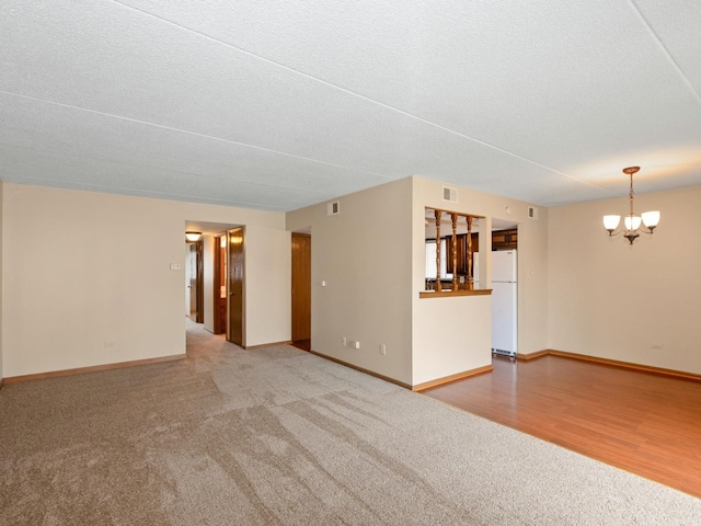 unfurnished living room featuring carpet floors, a chandelier, and baseboards