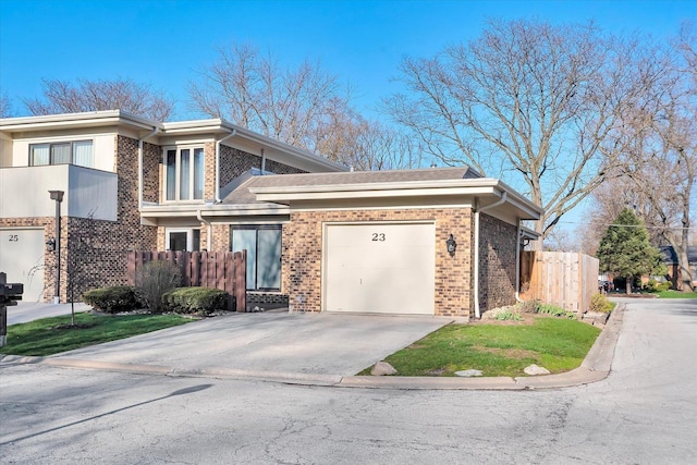 traditional-style home featuring an attached garage, concrete driveway, fence, and brick siding