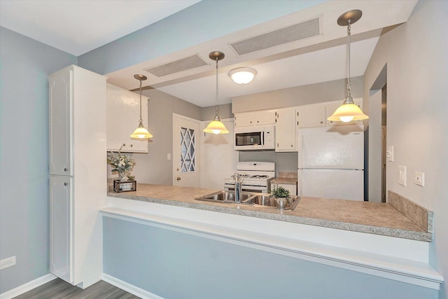 kitchen featuring dark wood-type flooring, hanging light fixtures, white cabinets, and white appliances