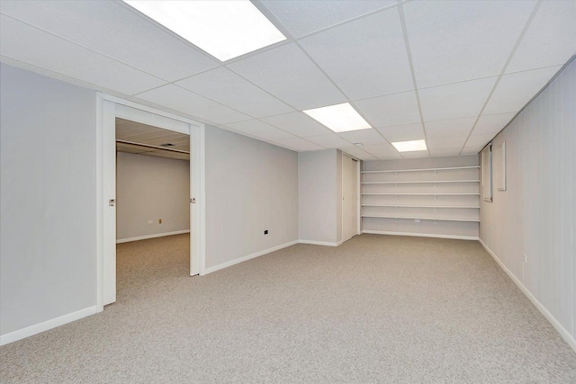 finished basement with baseboards, a drop ceiling, and carpet