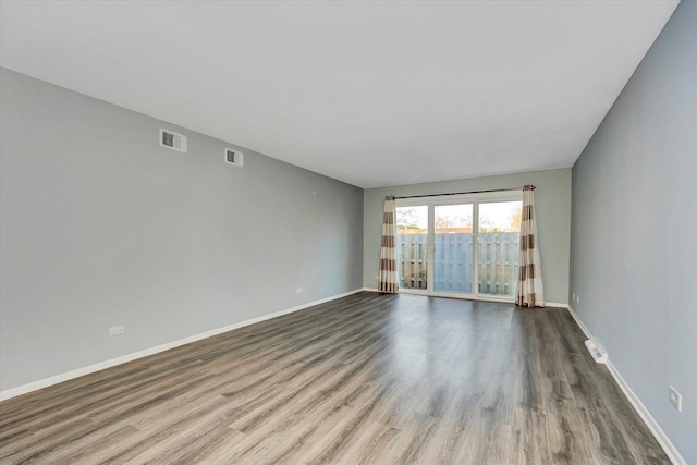 spare room featuring visible vents, baseboards, and wood finished floors