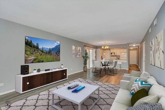 living area featuring a chandelier, light wood-type flooring, baseboards, and visible vents