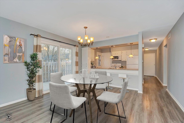 dining area with light wood finished floors, baseboards, and an inviting chandelier