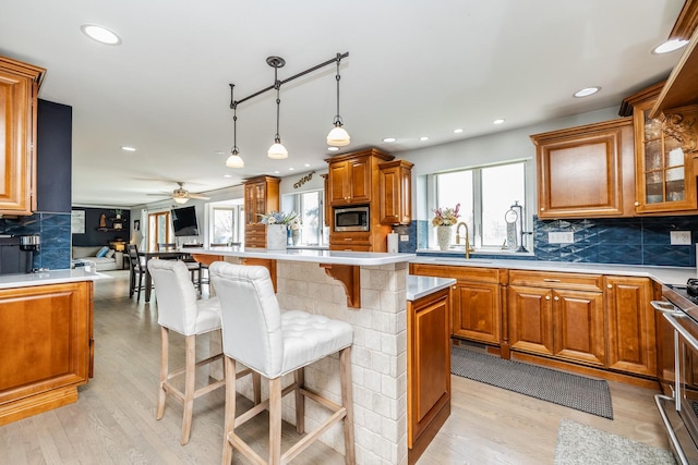 8001 William Dr, Willowbrook, IL 60527 - kitchen featuring stainless steel microwave, a breakfast bar, light wood-style flooring, brown cabinetry, and decorative backsplash