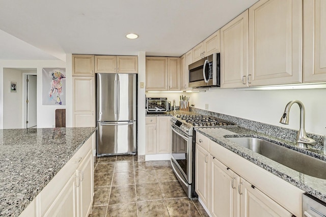 kitchen with a sink, dark stone countertops, stainless steel appliances, recessed lighting, and a toaster