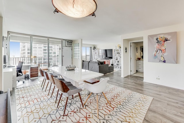 dining area featuring baseboards, a wall mounted air conditioner, and wood finished floors