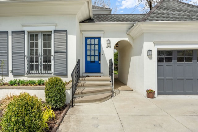 7968 Iowa St, River Forest, IL 60305 - view of exterior entry featuring concrete driveway, stucco siding, roof with shingles, and a garage