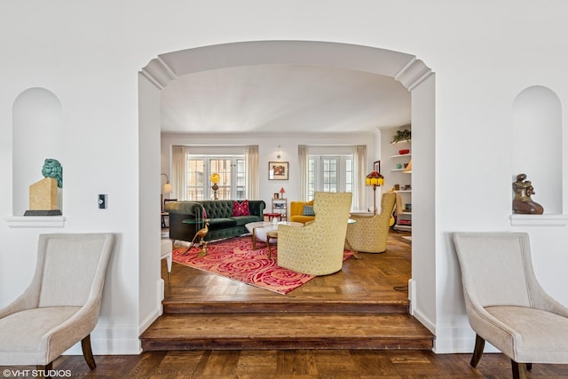 hall with baseboards, marble finish floor, and arched walkways