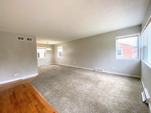 carpeted spare room featuring baseboards, visible vents, and an inviting chandelier