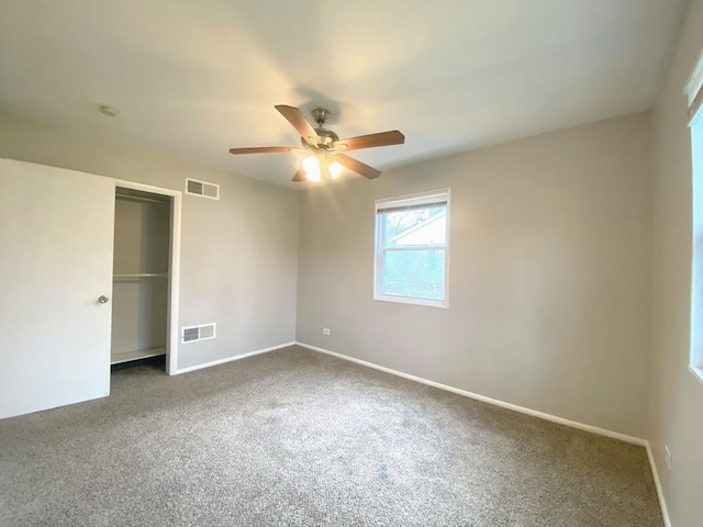 unfurnished bedroom with a closet, dark colored carpet, visible vents, and baseboards