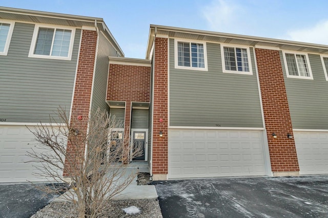 exterior space with an attached garage, driveway, and brick siding