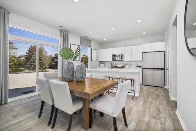 dining area with light wood finished floors, baseboards, visible vents, and recessed lighting