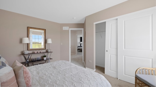 bedroom with a closet, baseboards, light colored carpet, and visible vents