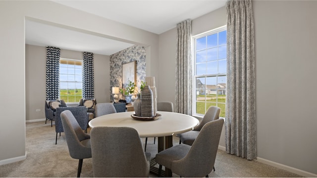 dining space featuring baseboards and light carpet