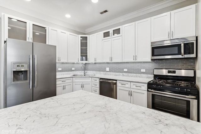kitchen featuring visible vents, tasteful backsplash, light stone counters, a sink, and appliances with stainless steel finishes