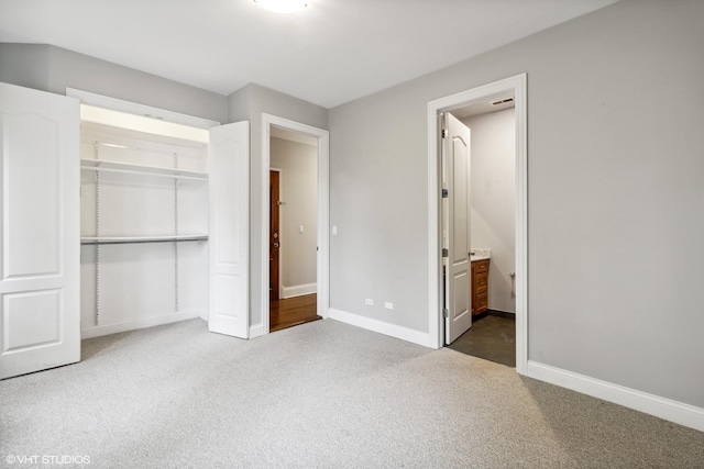 unfurnished bedroom featuring carpet flooring, baseboards, connected bathroom, and a closet