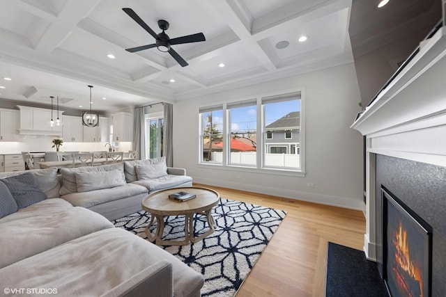 living area featuring a fireplace with flush hearth, light wood-style flooring, recessed lighting, and coffered ceiling
