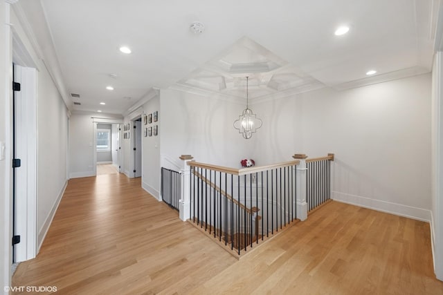 corridor with light wood-style floors, an upstairs landing, and ornamental molding
