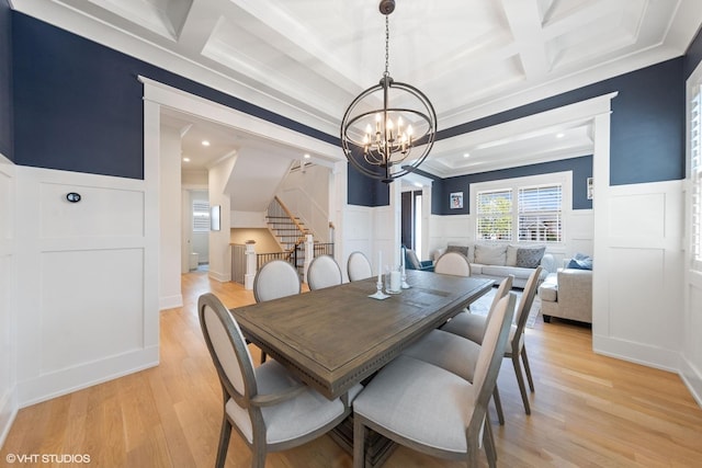 dining area with an inviting chandelier, coffered ceiling, stairway, crown molding, and a decorative wall