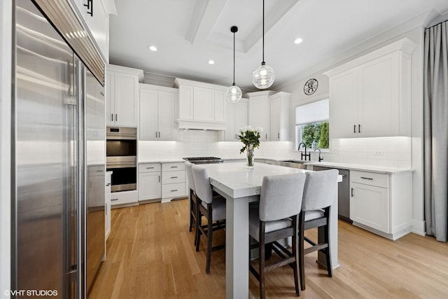 kitchen featuring white cabinets, a kitchen breakfast bar, stainless steel appliances, a sink, and a center island