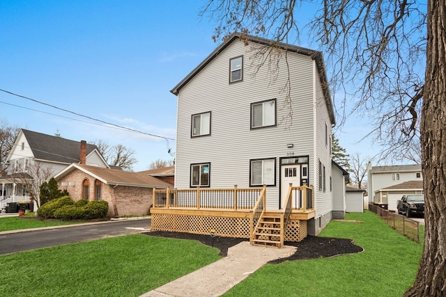 rear view of property featuring a deck, fence, and a lawn