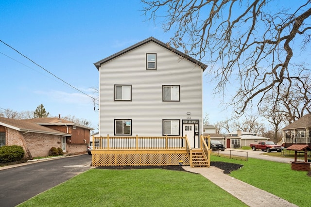 view of front of house with aphalt driveway, a deck, and a front lawn
