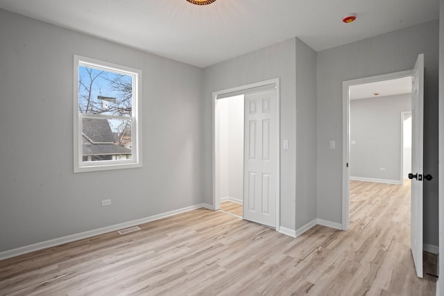 unfurnished bedroom with light wood finished floors, visible vents, and baseboards