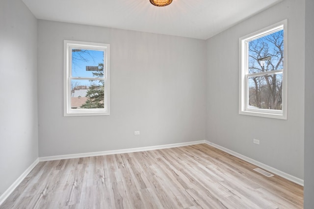 spare room featuring visible vents, baseboards, and light wood-style floors