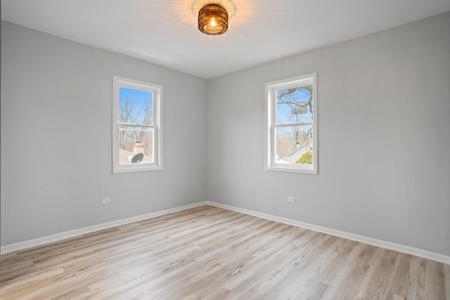 spare room featuring light wood finished floors, baseboards, and visible vents