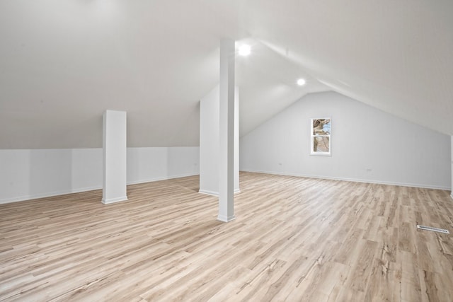 additional living space featuring baseboards, light wood-type flooring, and vaulted ceiling
