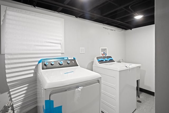 clothes washing area with baseboards, separate washer and dryer, and laundry area