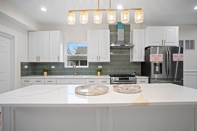 kitchen with a sink, wall chimney exhaust hood, white cabinets, and stainless steel appliances