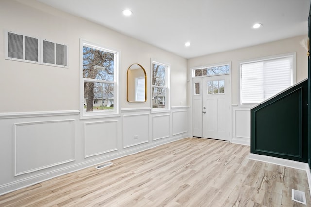 foyer entrance with a decorative wall, visible vents, and a wainscoted wall