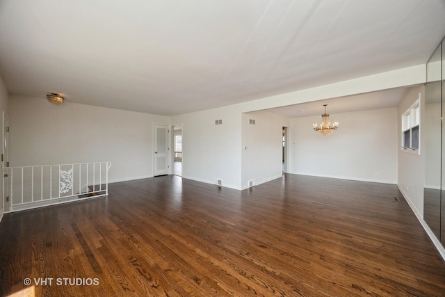 unfurnished room with a chandelier, baseboards, dark wood-style floors, and visible vents