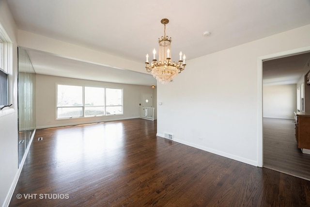 empty room with dark wood-style flooring, visible vents, baseboards, and an inviting chandelier