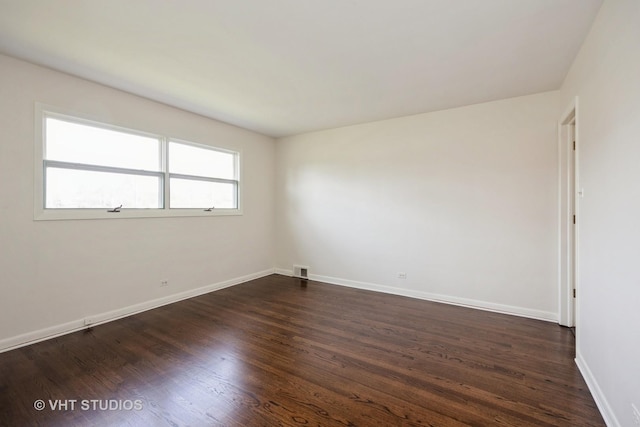 unfurnished room with dark wood-style flooring, baseboards, and visible vents