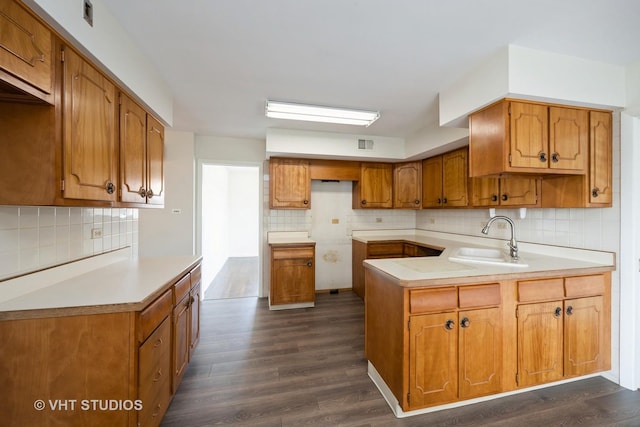 kitchen with a sink, tasteful backsplash, and dark wood finished floors