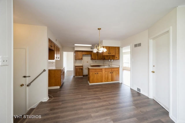 kitchen featuring tasteful backsplash, visible vents, a notable chandelier, and dark wood-style floors