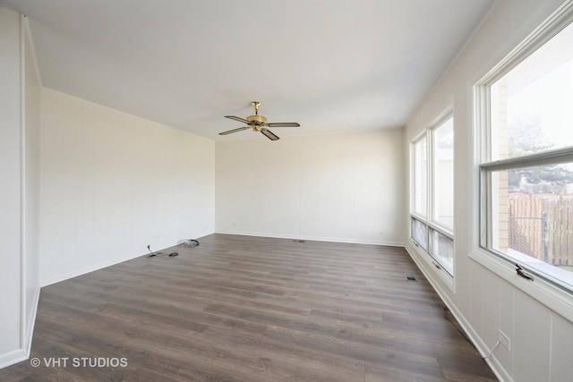 empty room with dark wood-type flooring, visible vents, ceiling fan, and baseboards