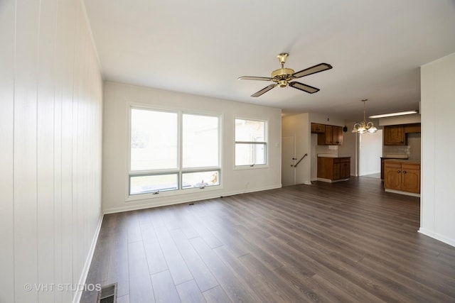 unfurnished living room with ceiling fan with notable chandelier, baseboards, dark wood-style floors, and visible vents
