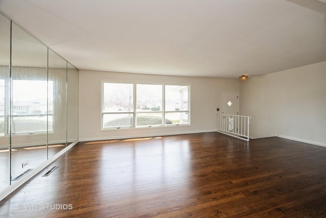 empty room with wood finished floors, baseboards, and visible vents