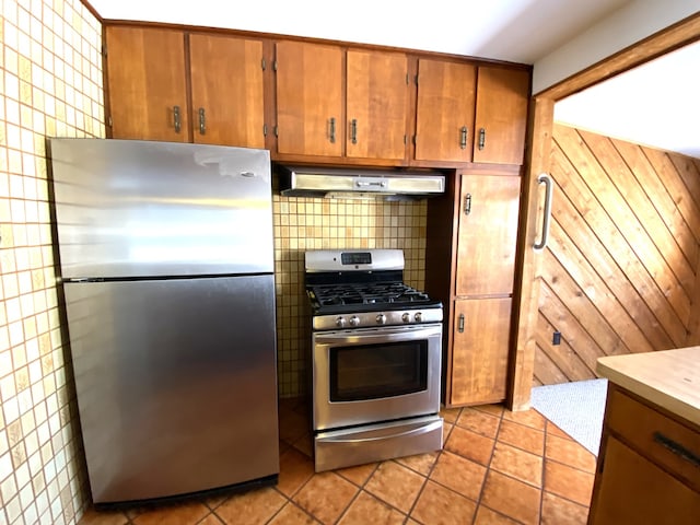 1657 Clay St, Woodstock, IL 60098 - kitchen featuring appliances with stainless steel finishes, under cabinet range hood, brown cabinets, tile walls, and light tile patterned floors