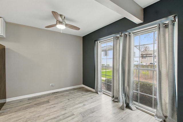 unfurnished room with baseboards, a ceiling fan, visible vents, and light wood-style flooring