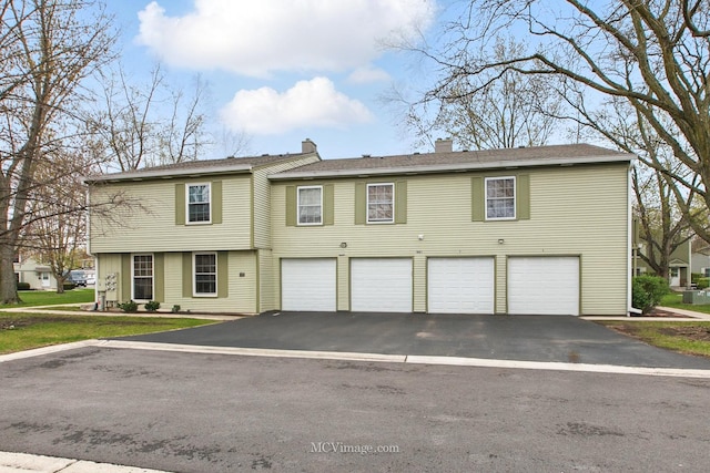 view of front of house with an attached garage, driveway, and a chimney