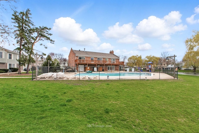 pool with a lawn, fence, and playground community