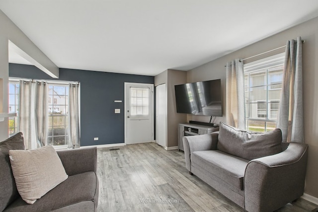 living room with baseboards, a healthy amount of sunlight, and light wood-style flooring