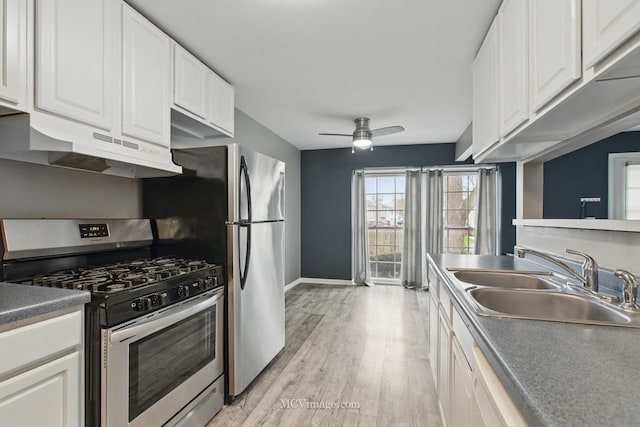 kitchen featuring under cabinet range hood, gas stove, a sink, and white cabinetry