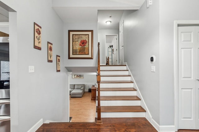staircase featuring wood finished floors and baseboards